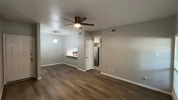 an empty room with wooden floor and a ceiling fan