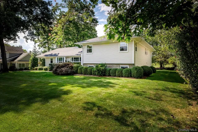 a view of a house with a big yard and large trees