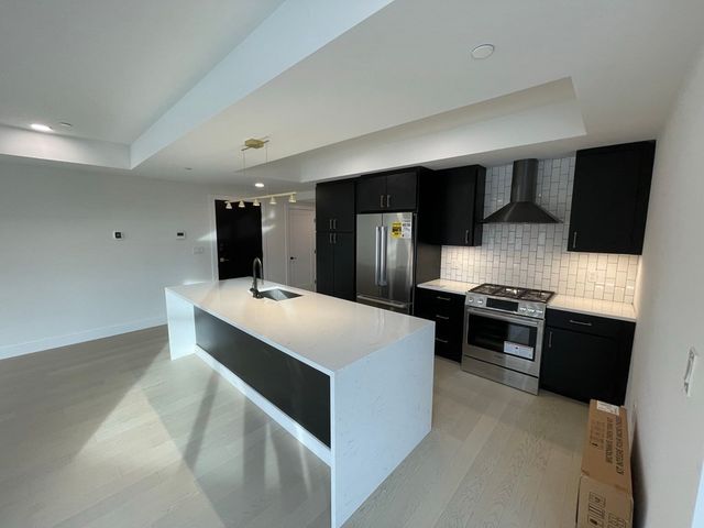 a large white kitchen with a sink and dishwasher a stove top oven with wooden floor