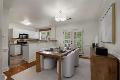 a kitchen with stainless steel appliances granite countertop a stove top oven a sink dishwasher a dining table and chairs with wooden floor