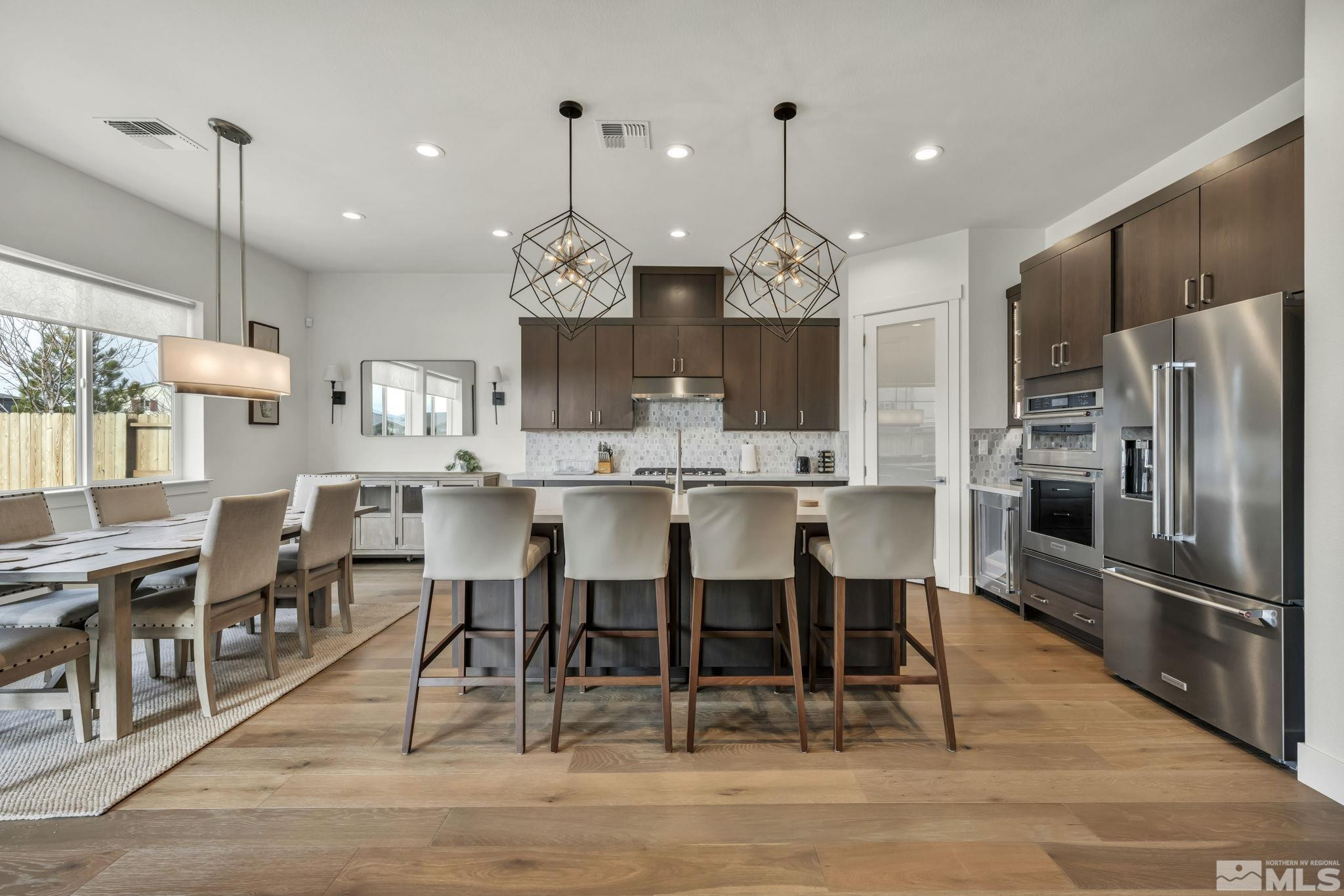 9525 Copper Sky Drive Reno, NV 89521 - Photo 11 of 40 a kitchen with stainless steel appliances kitchen island granite countertop a dining table chairs refrigerator and microwave