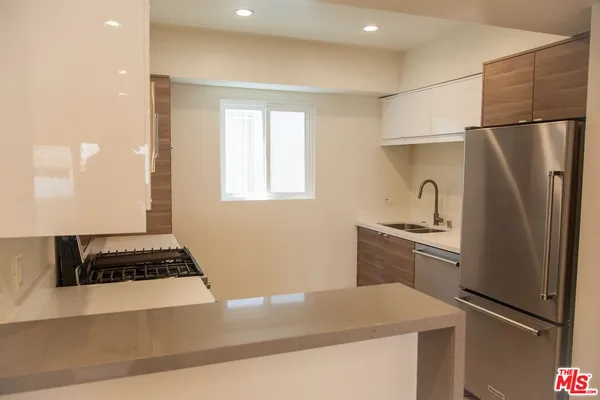 a kitchen with granite countertop a refrigerator and a stove top oven