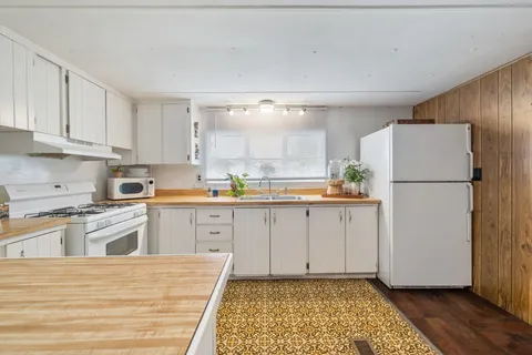 a kitchen with a refrigerator a stove top oven and cabinets