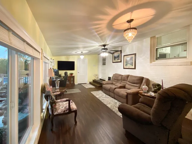 a living room with furniture kitchen view and a chandelier