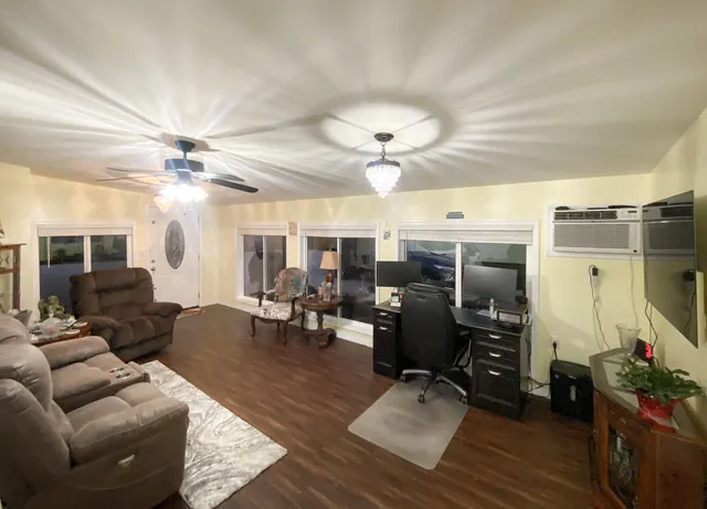 a living room with furniture a chandelier and a dining table with wooden floor