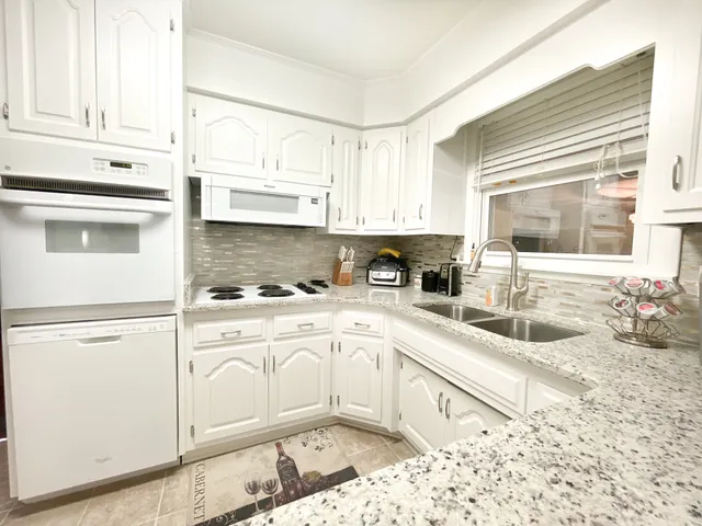 a kitchen with granite countertop a refrigerator stove microwave and cabinets