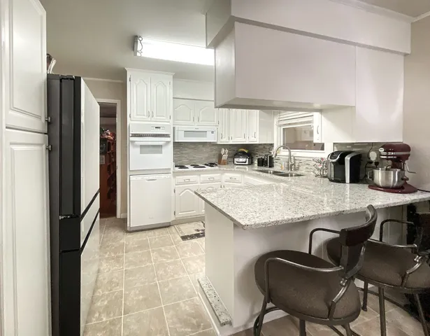 a living room with stainless steel appliances kitchen island granite countertop furniture a rug and white kitchen