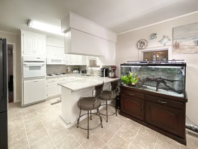 a kitchen with a refrigerator a stove a sink and white cabinets with wooden floor