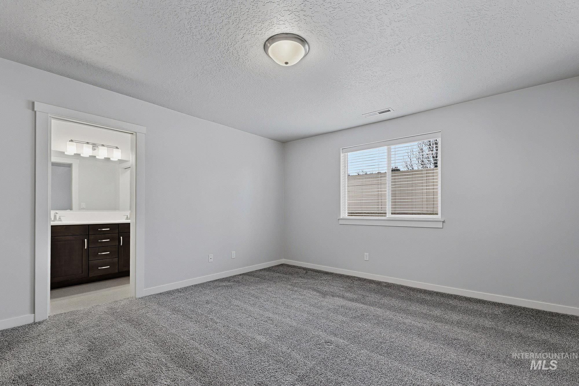 3065 North Summerbrook Avenue Meridian, ID 83646 - Photo 17 of 33 Unfurnished bedroom featuring light colored carpet, a textured ceiling, and ensuite bathroom