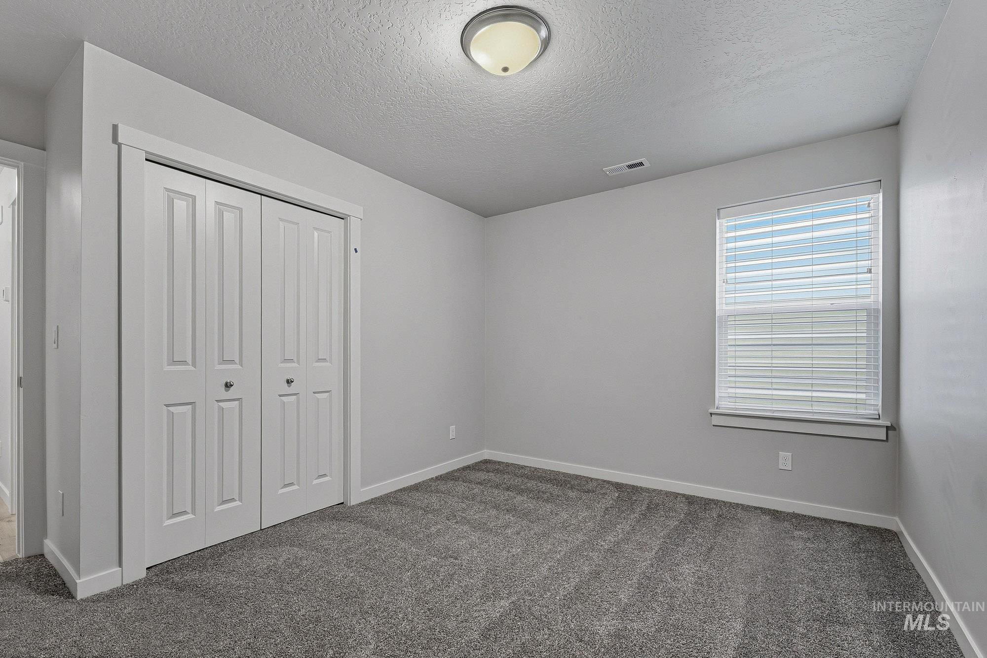 3065 North Summerbrook Avenue Meridian, ID 83646 - Photo 24 of 33 Unfurnished bedroom with dark carpet, a closet, and a textured ceiling