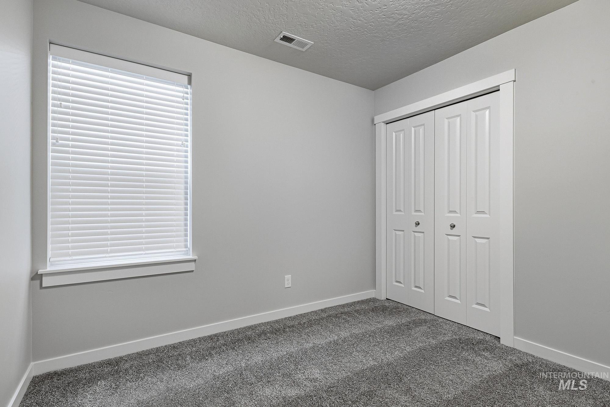 3065 North Summerbrook Avenue Meridian, ID 83646 - Photo 25 of 33 Unfurnished bedroom featuring a textured ceiling, dark colored carpet, and a closet