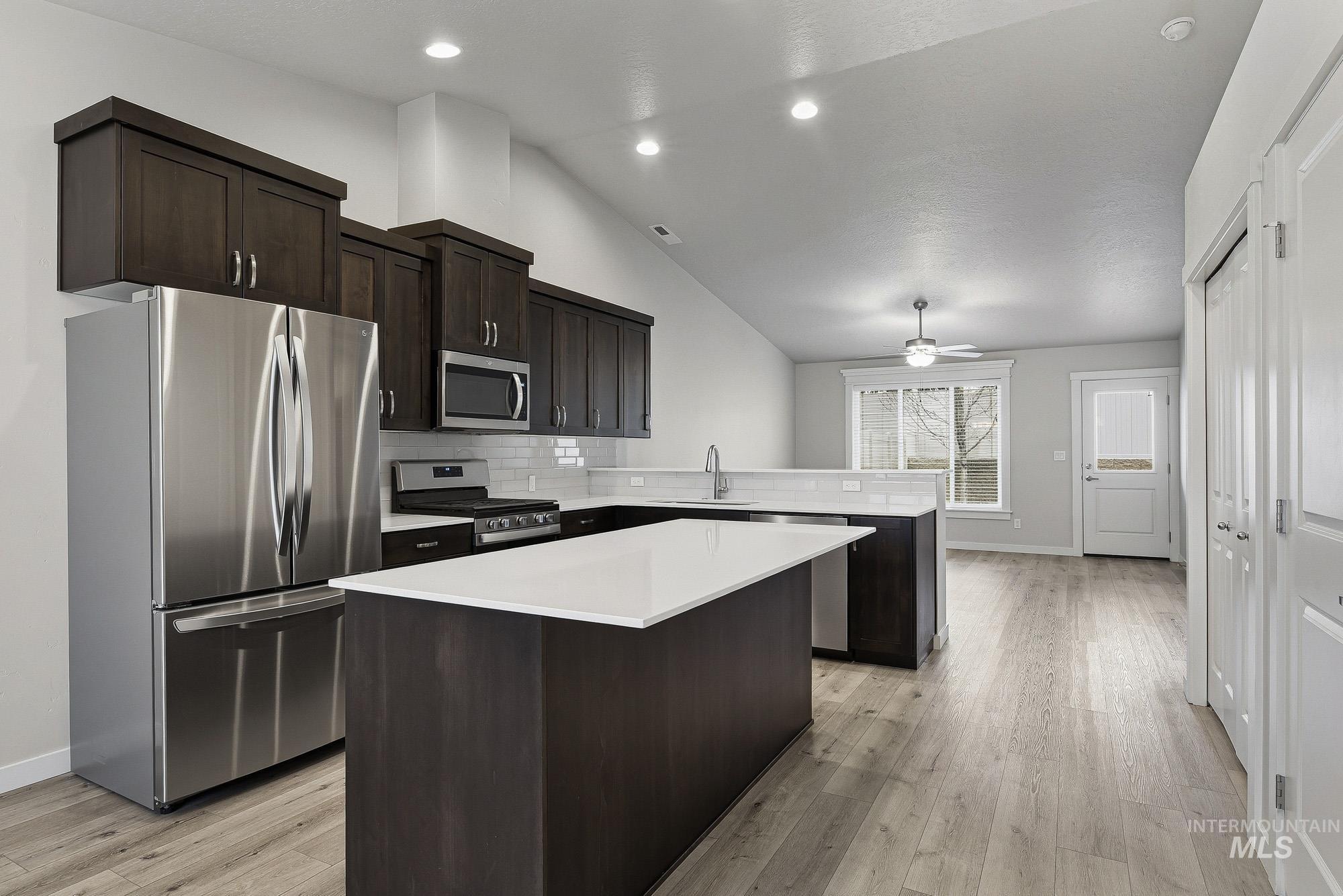 3065 North Summerbrook Avenue Meridian, ID 83646 - Photo 5 of 33 Kitchen with stainless steel appliances, a kitchen island, lofted ceiling, dark wood finish cabinets, and light wood-style floors