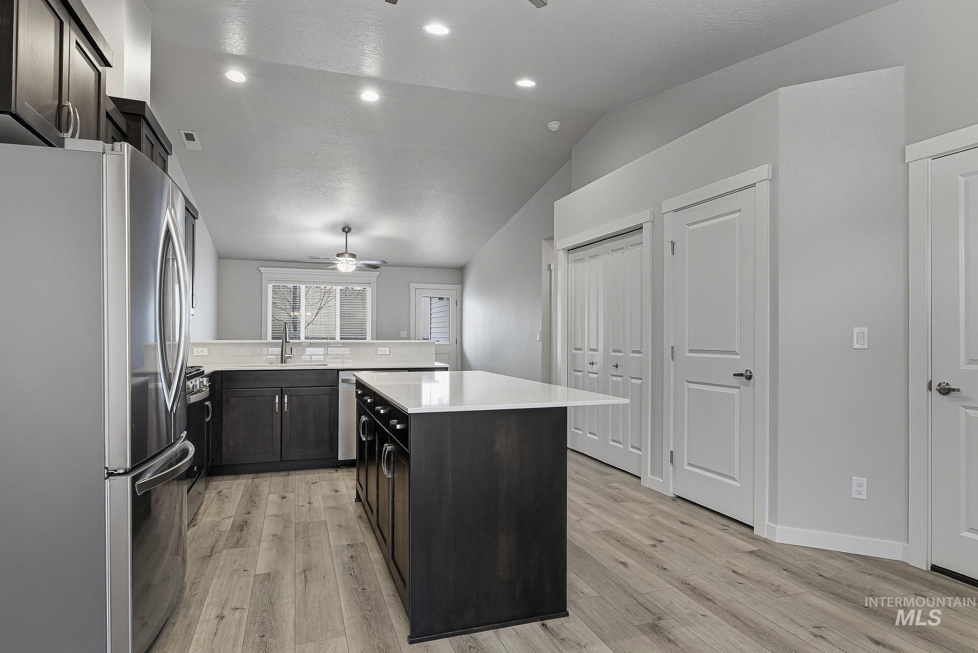 3065 North Summerbrook Avenue Meridian, ID 83646 - Photo 7 of 33 Kitchen with stainless steel appliances, a ceiling fan, lofted ceiling, light wood-style floors, and dark wood finish cabinetry