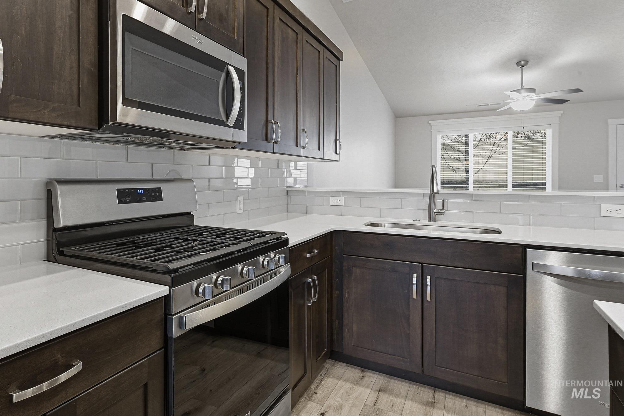 3065 North Summerbrook Avenue Meridian, ID 83646 - Photo 10 of 33 Kitchen with stainless steel appliances, dark wood finish cabinets, lofted ceiling, a ceiling fan, and tasteful backsplash