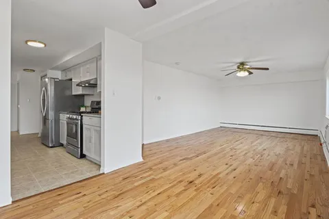 a view of empty room with wooden floor and fan