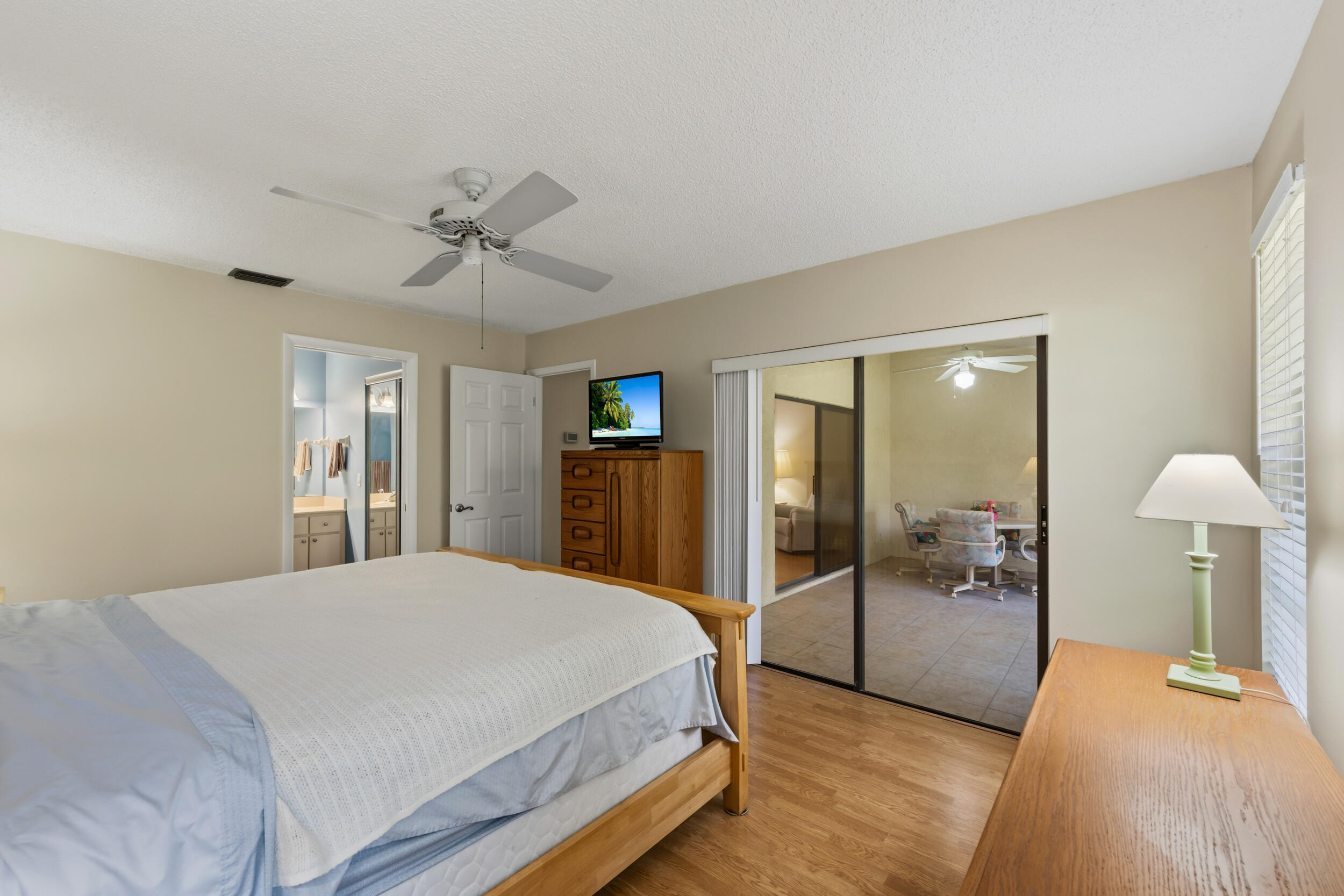 7873 Southeast Sugar Sand Circle Hobe Sound, FL 33455 - Photo 16 of 35 a spacious bedroom with a bed and a chandelier