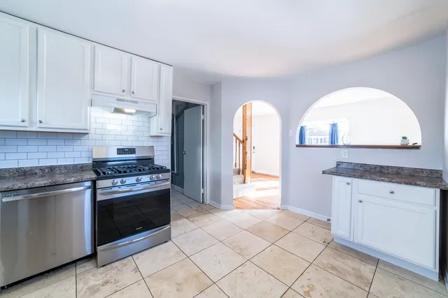 a kitchen with white cabinets and appliances