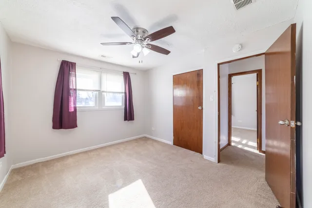 an empty room with windows and ceiling fan