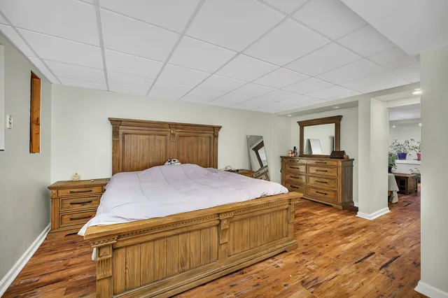 a bedroom with a bed and a walk in closet with wooden floor