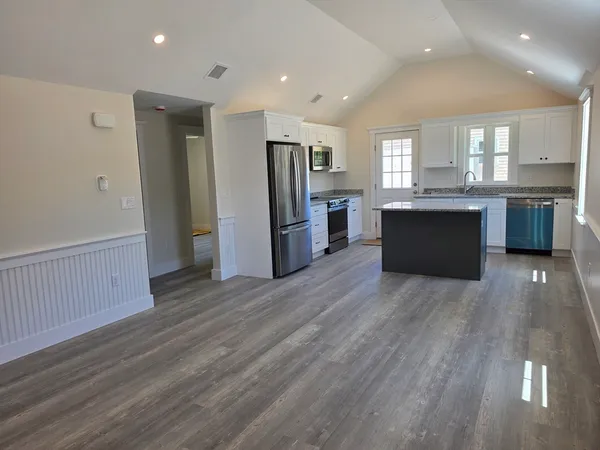 a large kitchen with a wooden floor and a refrigerator