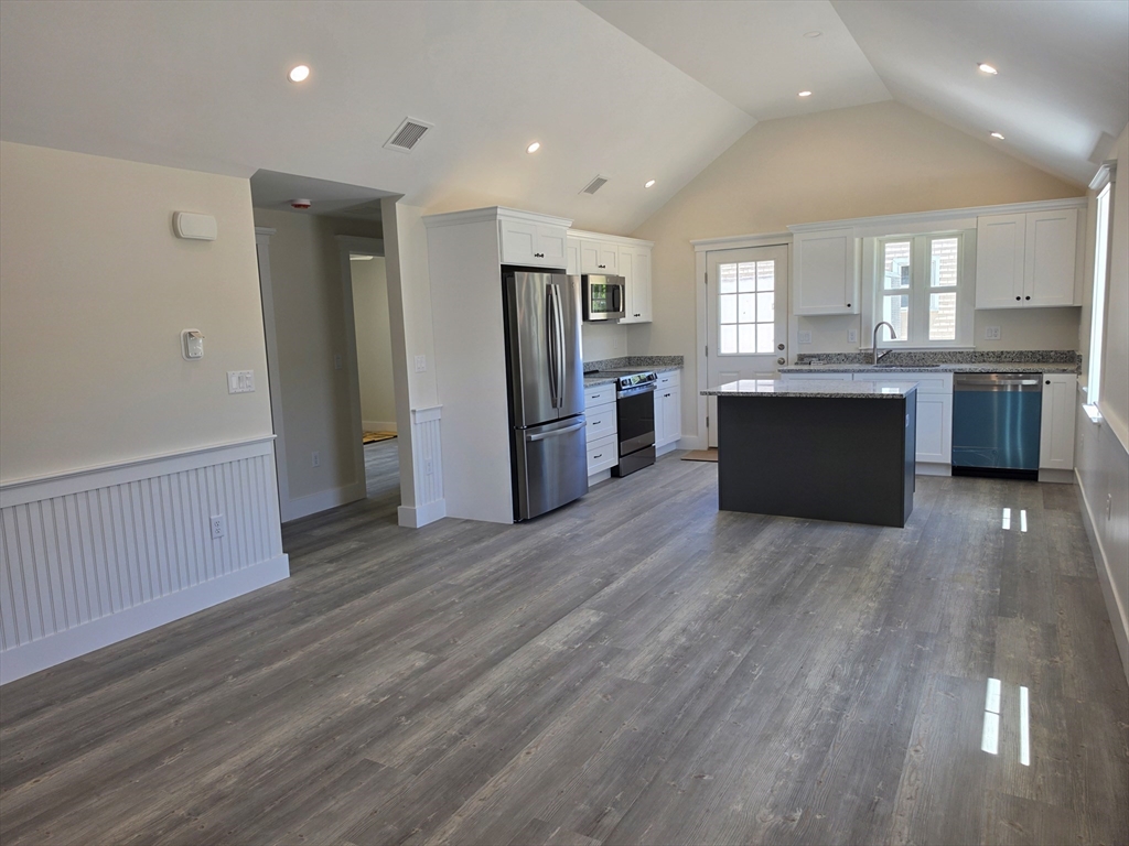 a large kitchen with a wooden floor and a refrigerator
