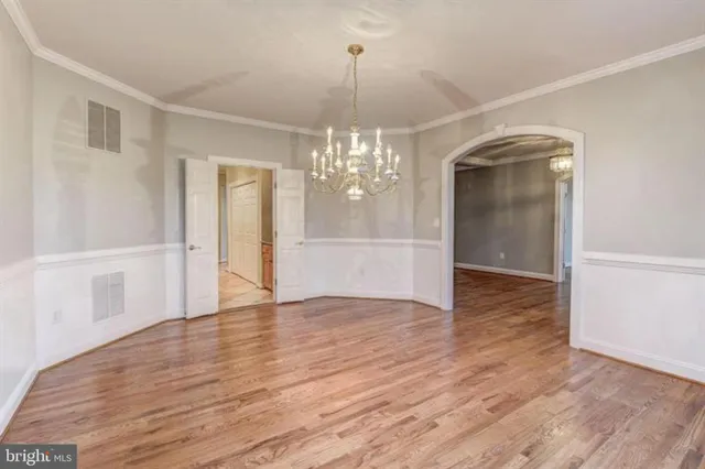 a view of an empty room with wooden floor and workspace