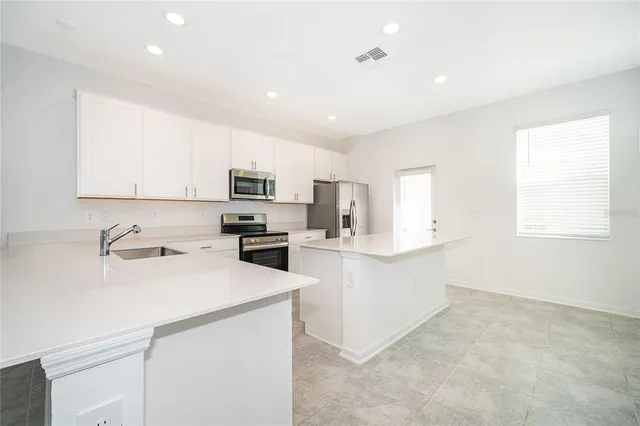 a kitchen with a sink a counter top space stainless steel appliances and cabinets
