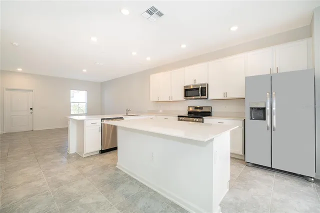 a kitchen with a sink a refrigerator and white cabinets