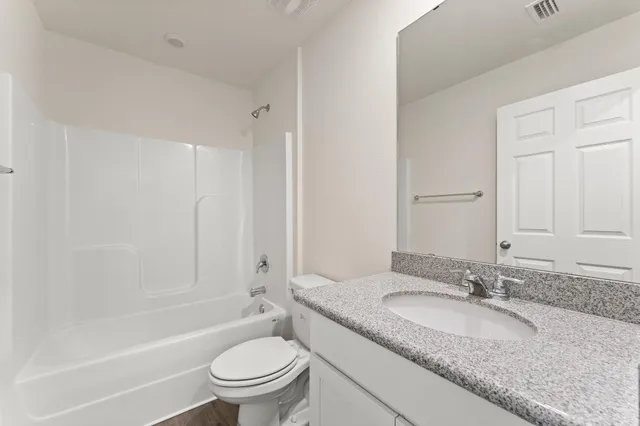 a bathroom with a granite countertop sink a toilet and a large mirror