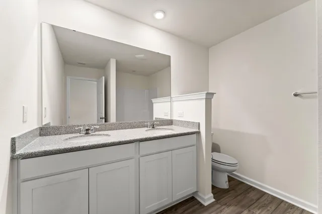 a bathroom with a granite countertop sink a toilet and a mirror