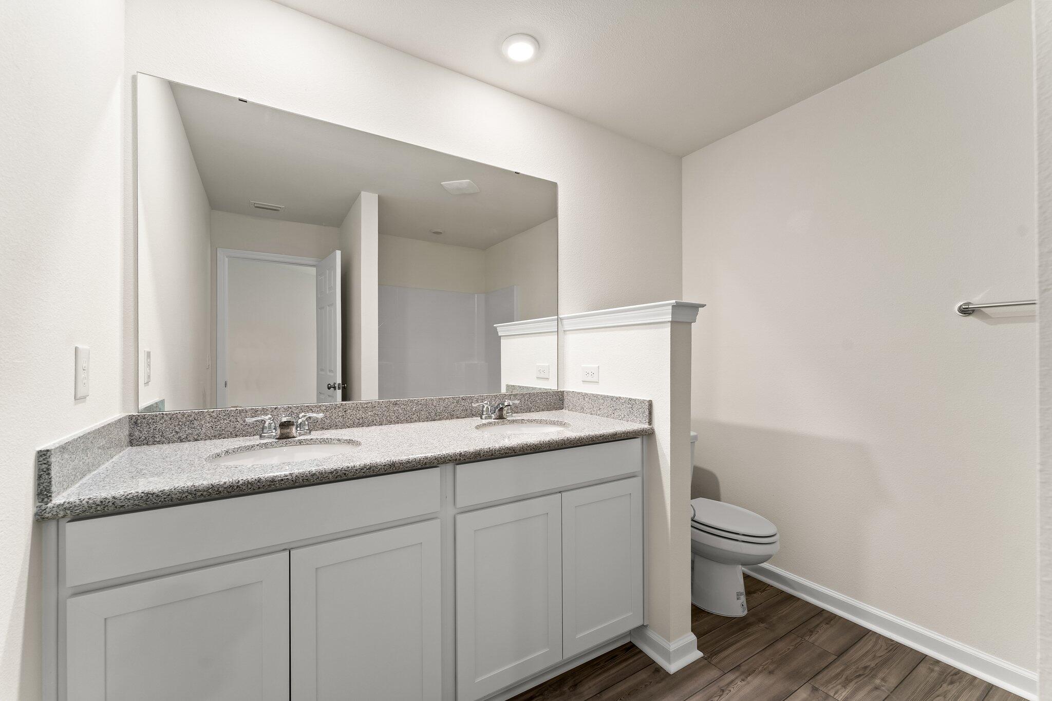 794 Riverwalk Circle Freeport, FL 32439 - Photo 26 of 31 a bathroom with a granite countertop sink a toilet and a mirror