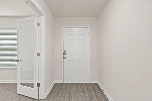 an empty room with wooden floor and windows