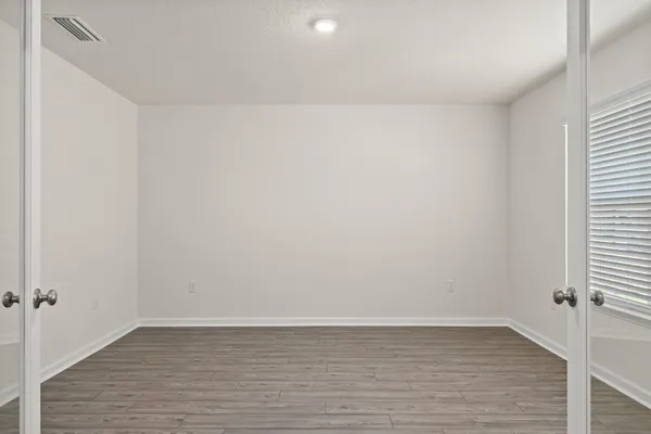 a view of an empty room with wooden floor and a window