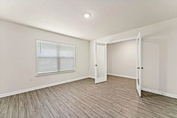 an empty room with wooden floor and windows