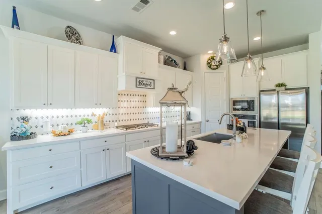a kitchen with sink and white cabinets with wooden floor
