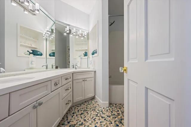 a spacious bathroom with a double vanity sink a mirror and a shower