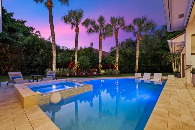 a view of swimming pool with lounge chair and palm trees