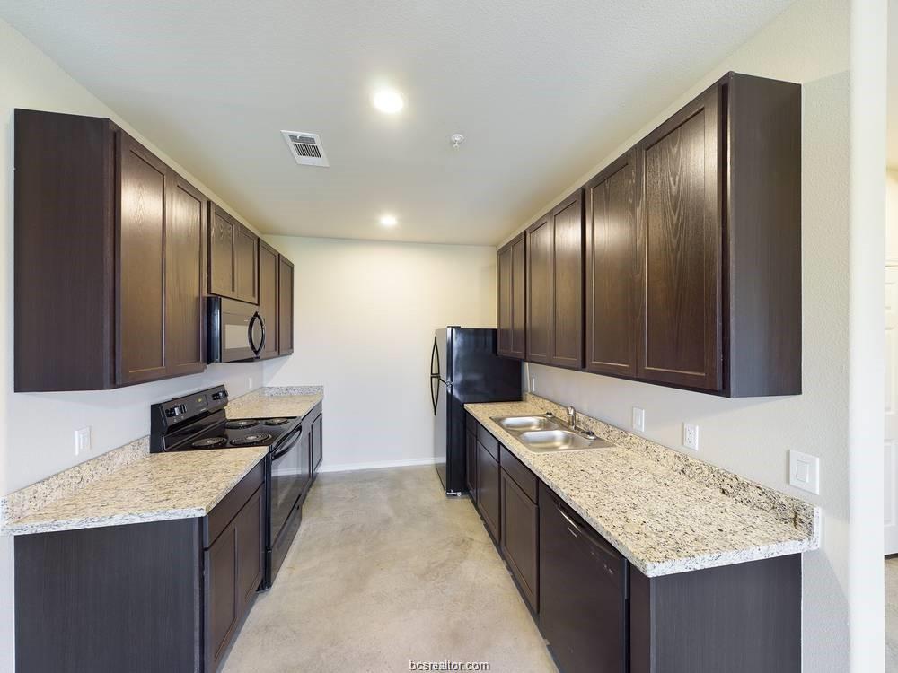 2910 Town Square Avenue, Unit 2607 Bryan, TX 77802 - Photo 3 of 7 a kitchen with stainless steel appliances granite countertop a sink stove and refrigerator