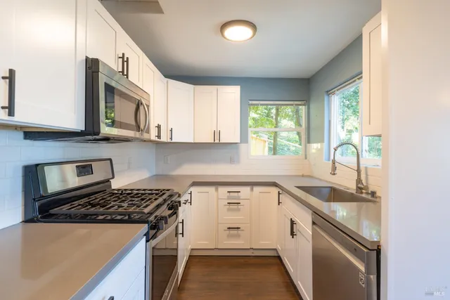 a kitchen with granite countertop a sink stove and cabinets