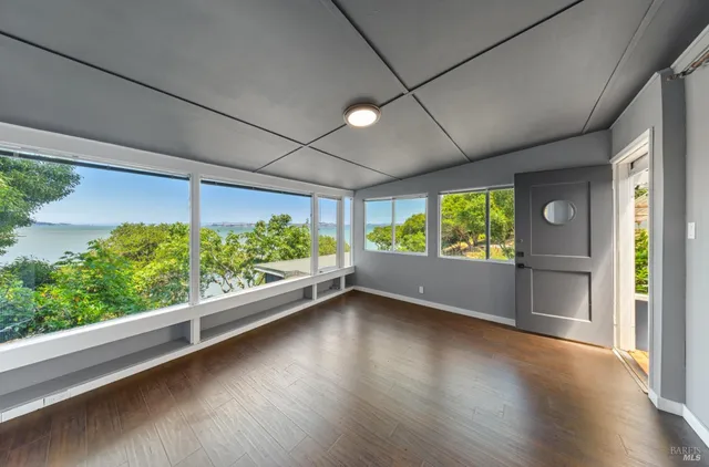 an empty room with wooden floor and windows