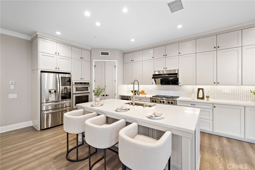 168 Bellini Irvine, CA 92602 - Photo 8 of 29 a kitchen with stainless steel appliances a stove a sink a microwave a refrigerator and white cabinets