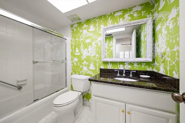 a bathroom with a granite countertop sink mirror vanity and toilet