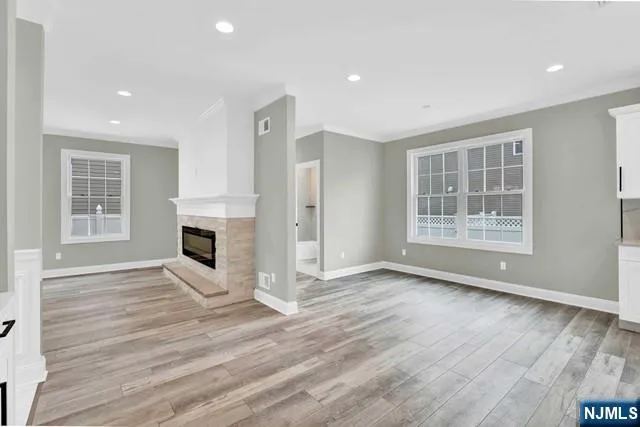 an empty room with wooden floor fireplace and windows