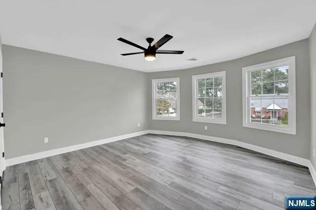a view of an empty room with a window and wooden floor