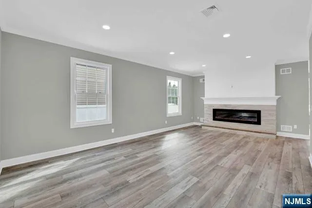 an empty room with wooden floor fireplace and windows