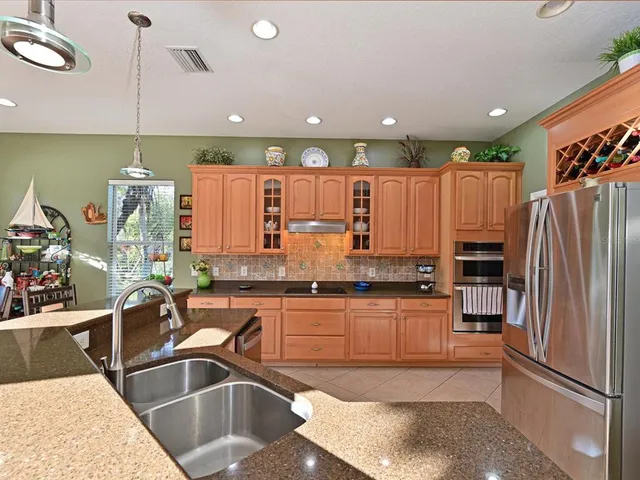 a kitchen with granite countertop a refrigerator a sink and wooden cabinets