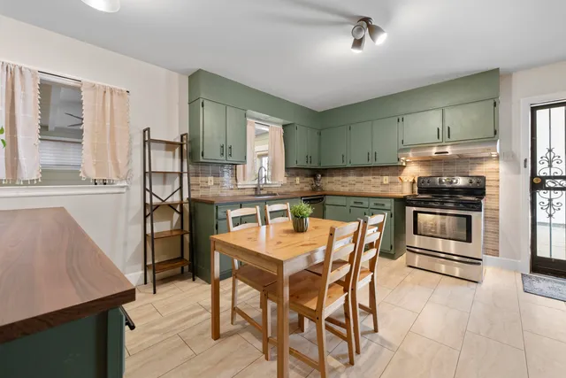 a kitchen with stainless steel appliances kitchen island granite countertop a table chairs and a refrigerator