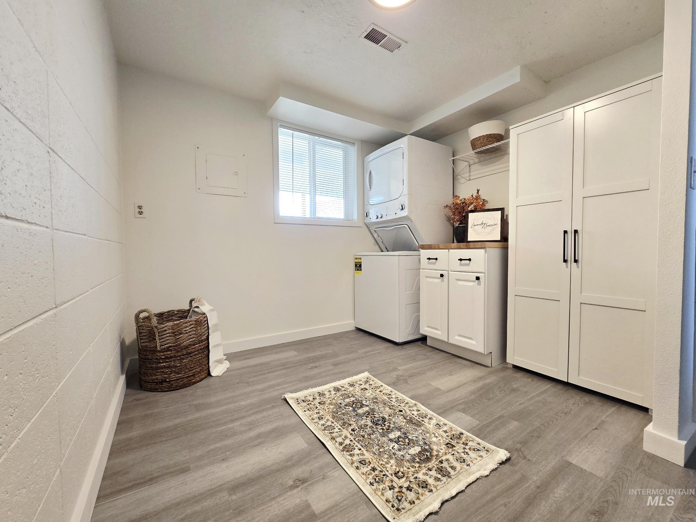 728 Northwest 8th Street Meridian, ID 83642 - Photo 9 of 18 Laundry area featuring cabinet space, stacked washer / drying machine, light wood-style floors, and concrete block wall