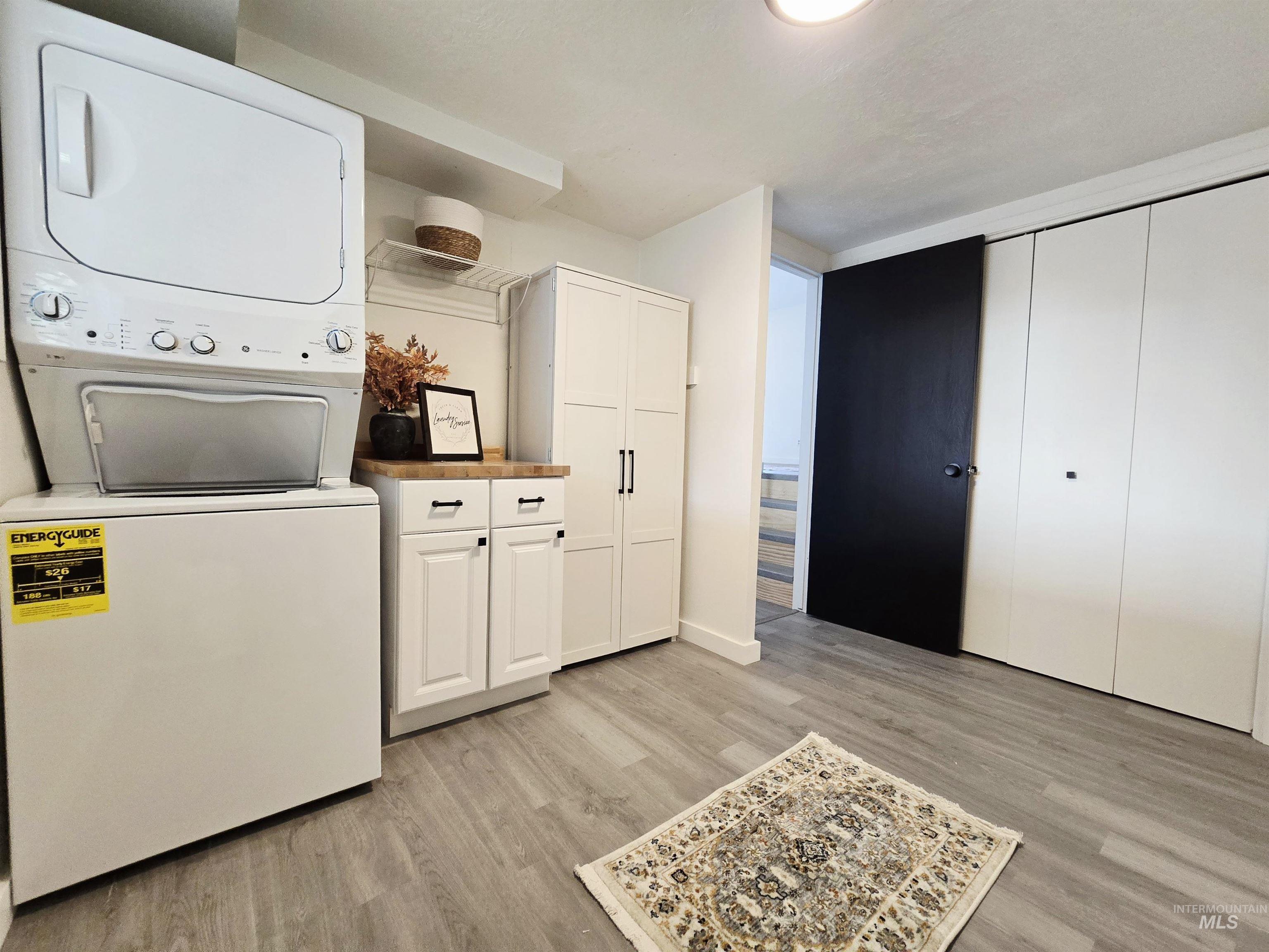 728 Northwest 8th Street Meridian, ID 83642 - Photo 10 of 18 Laundry area featuring light wood-type flooring, cabinet space, and stacked washing machine and dryer