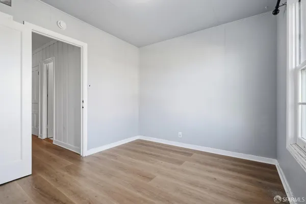 a view of an empty room with wooden floor and a window